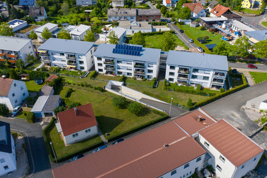 Aerial view of modern residential apartment buildings with solar panels on rooftops and green gardens in a suburban neighborhood Erlangen Bavaria Germany.