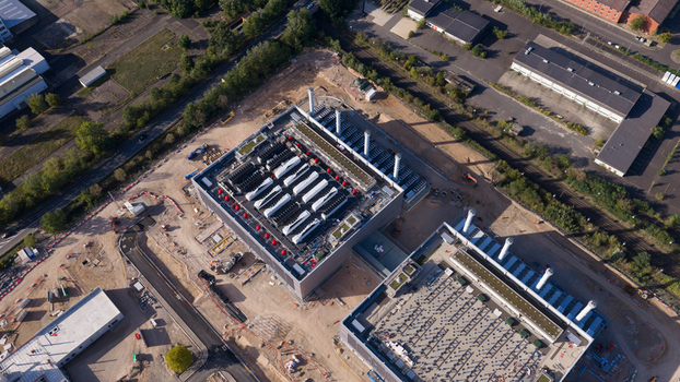 Aerial view of the Data4 Hanau data center facility featuring large industrial rooftops with cooling units surrounded by construction areas and infrastructure in Hanau Hessen Germany. Aerial view of the Data4 Hanau data center facility featuring large industrial rooftops with cooling units surrounded by construction areas and infrastructure in Hanau Hessen Germany.