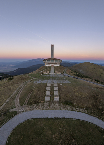 Aerial view of the Buzludzha Monument a brutalist structure on a mountain peak at sunset with paved paths and grassy slopes in Stara Zagora Bulgaria. Aerial view of the Buzludzha Monument a brutalist structure on a mountain peak at sunset with paved paths and grassy slopes in Stara Zagora Bulgaria.