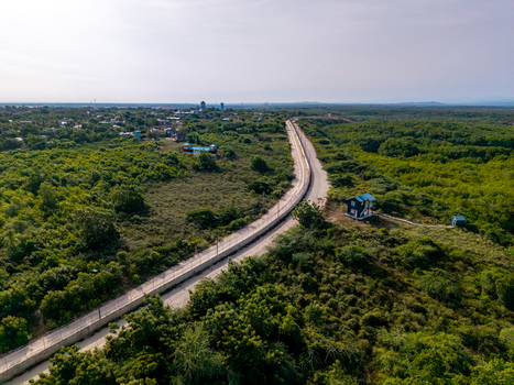 Aerial view of the border fence structure surrounded by lush green vegetation and trees near the town of Pepillo Salcedo Monte Cristi Province Dominican Republic. Aerial view of the border fence structure surrounded by lush green vegetation and trees near the town of Pepillo Salcedo Monte Cristi Province Dominican Republic.