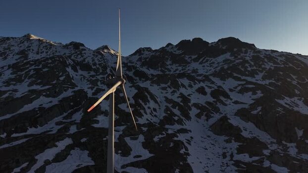Aerial view of a wind turbine at San Gottardo wind Park with snowy mountain peaks and rocky slopes under a clear sky at Airolo Ticino Switzerland.