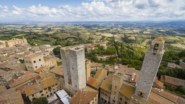 View of medieval towers pierce the skyline above terracotta roofs a landscape of rolling hills and vineyards unfolds bathed in Tuscan sun San Gimignano Tuscany Italy. View of medieval towers pierce the skyline above terracotta roofs a landscape of rolling hills and vineyards unfolds bathed in Tuscan sun San Gimignano Tuscany Italy.