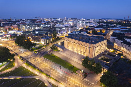 Aerial view of the Parliament House in Helsinki illuminated at night with surrounding city streets and glowing traffic light trails in Helsinki Uusimaa Finland.