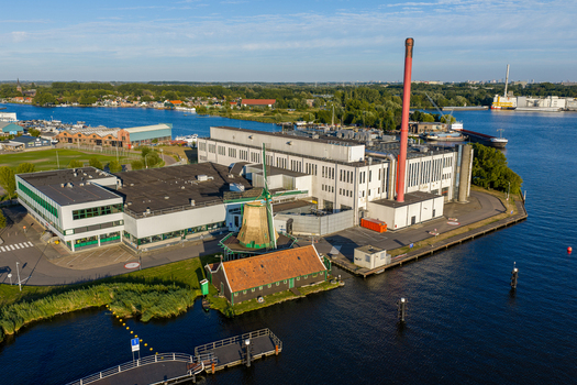 Aerial view of the Duyvis Production B.V. factory complex with its historic windmill and tall red chimney located in Zaandam Noord Holland Netherlands.
