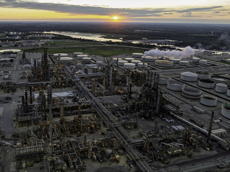 Aerial view of an oil refinery at sunset with storage tanks industrial infrastructure and smoke rising against the golden hour sky in Illinois United States.
