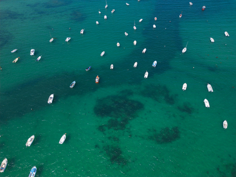Aerial view of numerous small white boats anchored in the turquoise waters of Plage de Port Blanc Penvenan Bretagne France. Aerial view of numerous small white boats anchored in the turquoise waters of Plage de Port Blanc Penvenan Bretagne France.