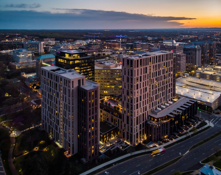 Reston Virginia United States 12 April 2020 Aerial view of modern high rise buildings and urban architecture in Reston during sunset with glowing lights and a clear sky.