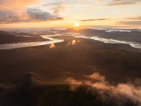 Aerial view of golden sunrise paints the meandering rivers and misty valleys of Iceland casting long shadows over the rugged terrain Highlands Iceland.