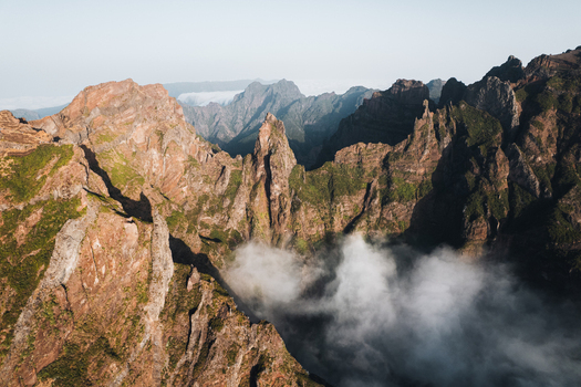 Aerial view of rugged peaks pierce through the clouds casting long shadows across the dramatic landscape Pico do Areeiro Madeira Portugal.
