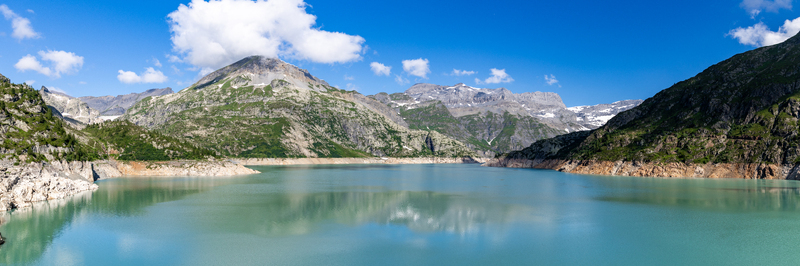 View of the turquoise waters of the Emosson Dam surrounded by rugged alpine mountains under a clear blue sky in Le Chatelard Fribourg Switzerland. View of the turquoise waters of the Emosson Dam surrounded by rugged alpine mountains under a clear blue sky in Le Chatelard Fribourg Switzerland.