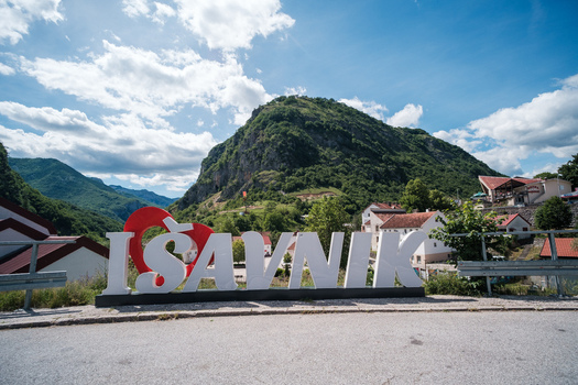 View of the Savnik town sign with a red heart symbol set against a backdrop of lush green mountains and a bright blue sky in Savnik Savnik Municipality Montenegro.