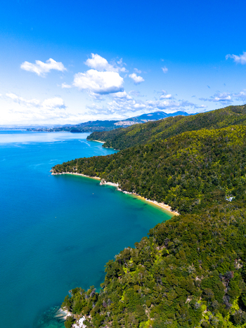 Aerial view of the vivid turquoise waters meeting the lush green coastline of Abel Tasman National Park Tasman Region New Zealand. Aerial view of the vivid turquoise waters meeting the lush green coastline of Abel Tasman National Park Tasman Region New Zealand.