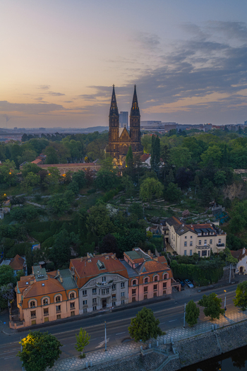 Aerial view of the Basilica of St Peter and St Paul in Vysehrad surrounded by lush greenery historic buildings and rooftops at sunset in Prague Prague Czechia.