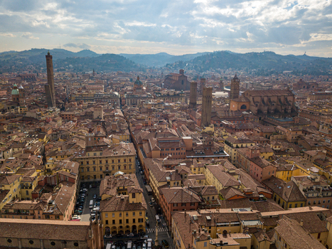 Aerial view of the Two Towers Garisenda and Asinelli rising above the historic red tiled rooftops and medieval architecture of the city center in Bologna Emilia Romagna Italy. Aerial view of the Two Towers Garisenda and Asinelli rising above the historic red tiled rooftops and medieval architecture of the city center in Bologna Emilia Romagna Italy.