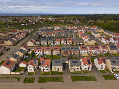 Aerial view of modern residential houses with solar panels on rooftops and green gardens near the coast in Edinburgh Scotland United Kingdom.