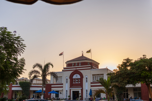 View of the historic Lido building of Gezira Club and lush greenery casting shadows in the warm light Zamalek Cairo Governorate Egypt. View of the historic Lido building of Gezira Club and lush greenery casting shadows in the warm light Zamalek Cairo Governorate Egypt.