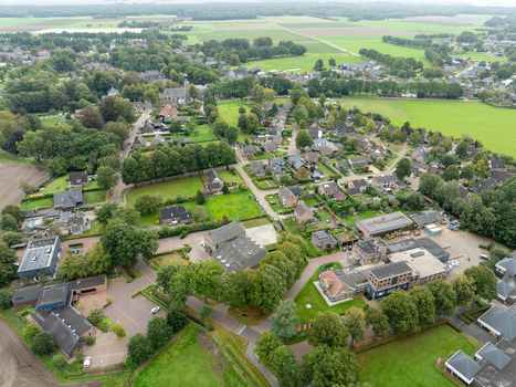 Aerial view of the historic Nicolaaskerk church surrounded by residential houses lush green trees and agricultural fields in Dwingeloo Drenthe Netherlands. Aerial view of the historic Nicolaaskerk church surrounded by residential houses lush green trees and agricultural fields in Dwingeloo Drenthe Netherlands.