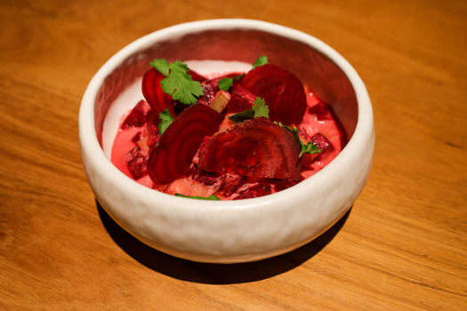 View of a gourmet beet salad with creamy dressing and fresh cilantro in a white ceramic bowl at Manta by Enrique Olvera in Cabo San Lucas Baja California Sur Mexico.