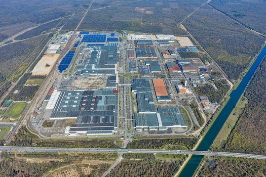 Aerial view of sprawling industrial complex with various buildings and solar panel installations surrounded by lush greenery Sausheim Grand Est France.
