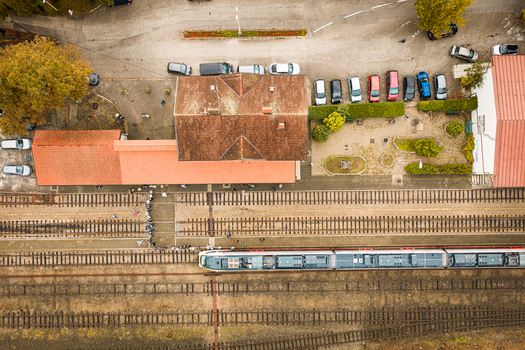 Aerial view of a train station with passengers waiting on the platform next to a train railway tracks and a nearby parking lot in Buzet Istria County Croatia.