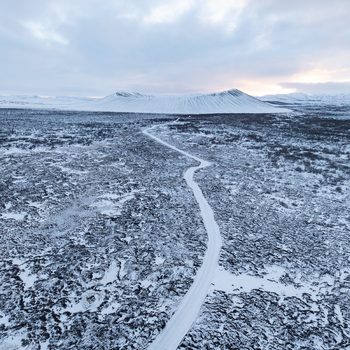 Aerial view of Hverfjall volcano surrounded by snow covered volcanic terrain and a winding road in Thingeyjarsveit Iceland. Aerial view of Hverfjall volcano surrounded by snow covered volcanic terrain and a winding road in Thingeyjarsveit Iceland.