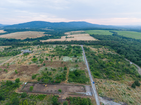 Aerial view of Strandzha Nature Park featuring rolling hills agricultural fields a rural road and a construction site with an excavator in Tsarevo Burgas Bulgaria.