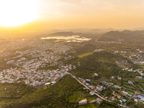 Aerial view of the city of Udaipur nestled among the Aravalli hills with lush green landscapes and golden sunset light over the lakes in Udaipur Rajasthan India.