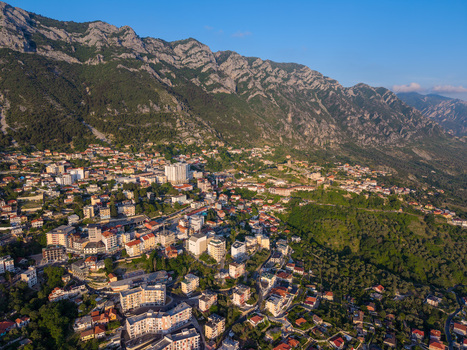 Aerial view of the historic town of Kruje nestled at the foot of rugged mountain peaks with residential buildings and green slopes in Kruje Durres County Albania.