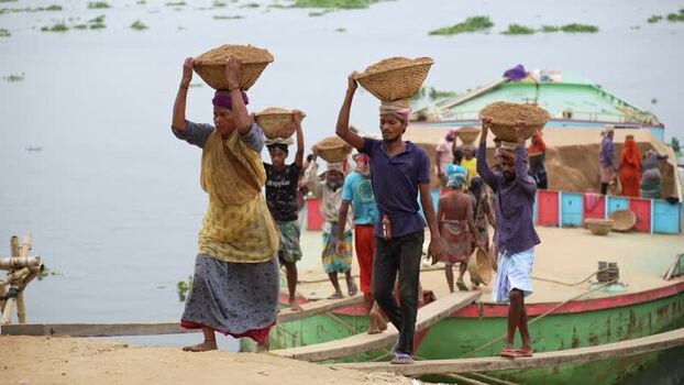 View of workers carrying baskets from a boat in Aminbazar Bangladesh.