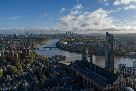 Aerial view of Lots Road Power Station and the River Thames with the city skyline under a cloudy blue sky London England United Kingdom. Aerial view of Lots Road Power Station and the River Thames with the city skyline under a cloudy blue sky London England United Kingdom.