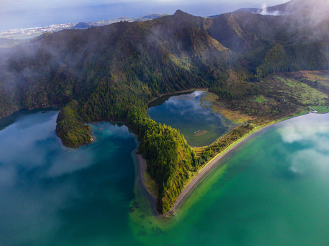 Aerial view of Lagoa do Fogo crater lake with turquoise water and lush green volcanic slopes under a misty sky in Agua de Alto Azores Portugal. Aerial view of Lagoa do Fogo crater lake with turquoise water and lush green volcanic slopes under a misty sky in Agua de Alto Azores Portugal.