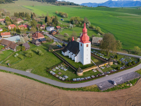Aerial view of the historic Church of Saint Ladislaus with its red tower and stone walls surrounded by green fields and mountains in Liptovske Matiasovce Zilina Region Slovakia.