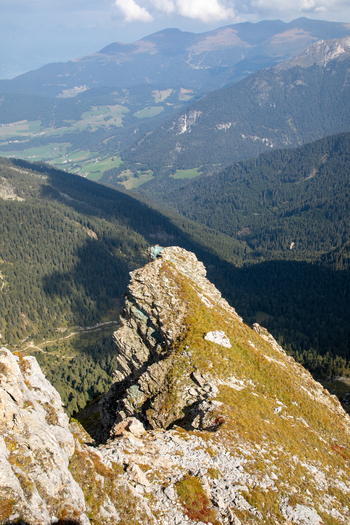 Aerial view of the rugged rocky ridge of the Dolomites with grassy slopes and deep forested valleys in Rocca Pietore Veneto Italy.
