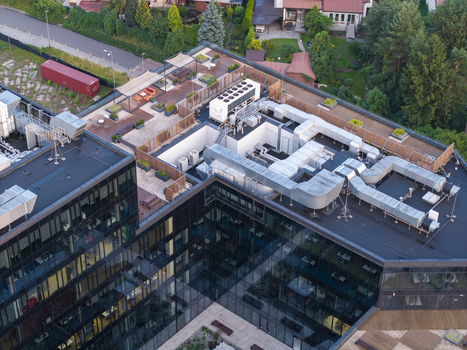 Aerial view of a modern office building rooftop featuring extensive HVAC ventilation systems a landscaped terrace with seating areas and glass facades in Krakow Lesser Poland Voivodeship Poland. Aerial view of a modern office building rooftop featuring extensive HVAC ventilation systems a landscaped terrace with seating areas and glass facades in Krakow Lesser Poland Voivodeship Poland.