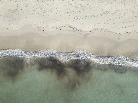 Aerial view of the white sandy Vik Strand beach with footprints on the shore and dark sediment swirling in the turquoise waves in Leknes Nordland Norway. Aerial view of the white sandy Vik Strand beach with footprints on the shore and dark sediment swirling in the turquoise waves in Leknes Nordland Norway.