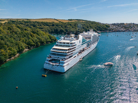 Fowey Cornwall United Kingdom 10 August 2026 Aerial view of a large cruise ship anchored in the Fowey River surrounded by small boats and the town. Fowey Cornwall United Kingdom 10 August 2026 Aerial view of a large cruise ship anchored in the Fowey River surrounded by small boats and the town.