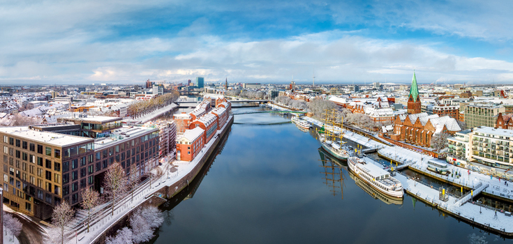 Aerial view of the Weser river featuring snow covered rooftops historic architecture St. Martin s Church and boats docked along the riverbank in Bremen Germany. Aerial view of the Weser river featuring snow covered rooftops historic architecture St. Martin s Church and boats docked along the riverbank in Bremen Germany.
