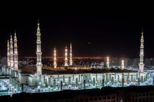 View of Al Masjid e Nabawi at night with its illuminated minarets and expansive courtyard glowing against the dark sky in Madinah Al Madinah Province Saudi Arabia.