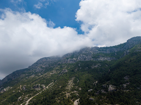 Aerial view of the rugged mountain peaks covered in lush green vegetation and white clouds under a blue sky Kruje Durres County Albania.