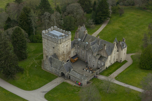 Aerial view of Drum Castle featuring its historic stone tower and surrounding green estate in Drumoak Scotland United Kingdom.