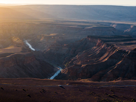 Aerial view of the Fish River Canyon s rugged terrain a ribbon of river snaking through the deep gorge contrasts with the warm sunlit cliffs Fish River Canyon Karas Region Namibia. Aerial view of the Fish River Canyon s rugged terrain a ribbon of river snaking through the deep gorge contrasts with the warm sunlit cliffs Fish River Canyon Karas Region Namibia.