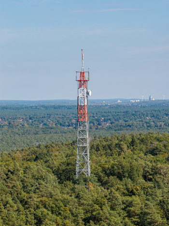 Aerial view of the Muggelberge radio antenna tower rising above the dense forest canopy under a clear blue sky in Berlin Berlin Germany. Aerial view of the Muggelberge radio antenna tower rising above the dense forest canopy under a clear blue sky in Berlin Berlin Germany.