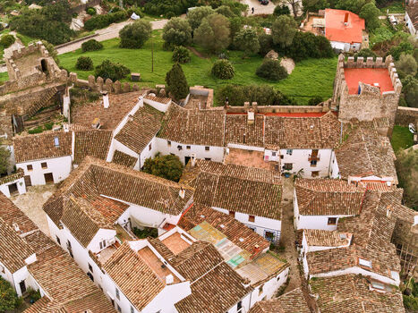 Aerial view of the ancient fortress with its weathered stone walls and red tiled roofs contrasting against the verdant landscape Castellar de la Frontera Andalucía Spain. Aerial view of the ancient fortress with its weathered stone walls and red tiled roofs contrasting against the verdant landscape Castellar de la Frontera Andalucía Spain.