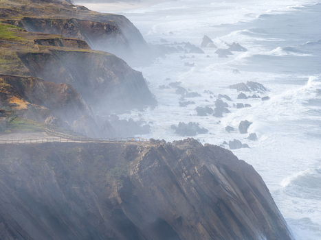 Aerial view of rugged cliffs shrouded in mist with crashing waves against the rocky coastline of Marinha Grande Leiria Portugal. Aerial view of rugged cliffs shrouded in mist with crashing waves against the rocky coastline of Marinha Grande Leiria Portugal.
