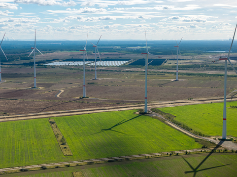 Aerial view of Windpark Forst Briesnig II featuring wind turbines on recultivated land of a former open pit mine with green fields and solar panels in the distance in Forst Brandenburg Germany. Aerial view of Windpark Forst Briesnig II featuring wind turbines on recultivated land of a former open pit mine with green fields and solar panels in the distance in Forst Brandenburg Germany.