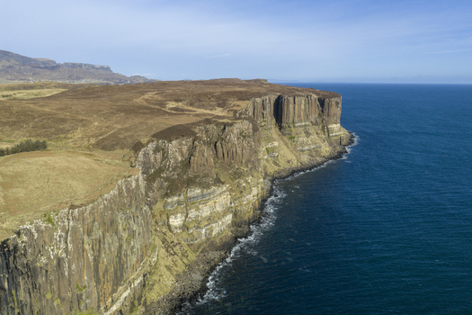 Aerial view of Kilt Rock and Mealt Falls with dramatic basalt columns and a waterfall plunging into the blue sea under a clear sky Isle of Skye Scotland United Kingdom. Aerial view of Kilt Rock and Mealt Falls with dramatic basalt columns and a waterfall plunging into the blue sea under a clear sky Isle of Skye Scotland United Kingdom.