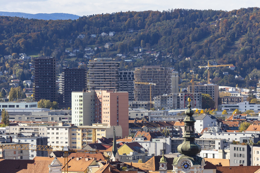 View of buildings and rooftops at the new Reininghaus city development district under the warm sunlight in a vibrant urban setting with forested hills Graz Styria Austria. View of buildings and rooftops at the new Reininghaus city development district under the warm sunlight in a vibrant urban setting with forested hills Graz Styria Austria.