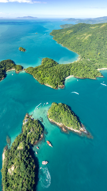 Aerial view of Lagoa Azul surrounded by lush green islands and turquoise waters with boats anchored in Angra dos Reis Rio de Janeiro Brazil.