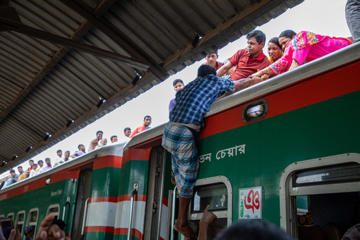 Dhaka Bangladesh 14 June 2018 View of people climbing onto the roof of a crowded train at Airport Railway Station with passengers helping each other under the station canopy. Dhaka Bangladesh 14 June 2018 View of people climbing onto the roof of a crowded train at Airport Railway Station with passengers helping each other under the station canopy.