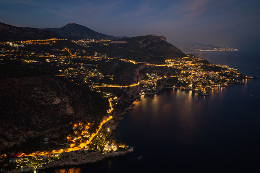 Aerial view of the coastal village of Eze illuminated at night featuring winding roads along the cliffs Mediterranean Sea and mountain landscape in Eze Provence Alpes Cote d Azur France. Aerial view of the coastal village of Eze illuminated at night featuring winding roads along the cliffs Mediterranean Sea and mountain landscape in Eze Provence Alpes Cote d Azur France.